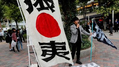 A man speaks on a loudspeaker with leaflets denouncing South Korean boy band BTS outside Tokyo Dome. Kim Kyung-Hoon / Reuters