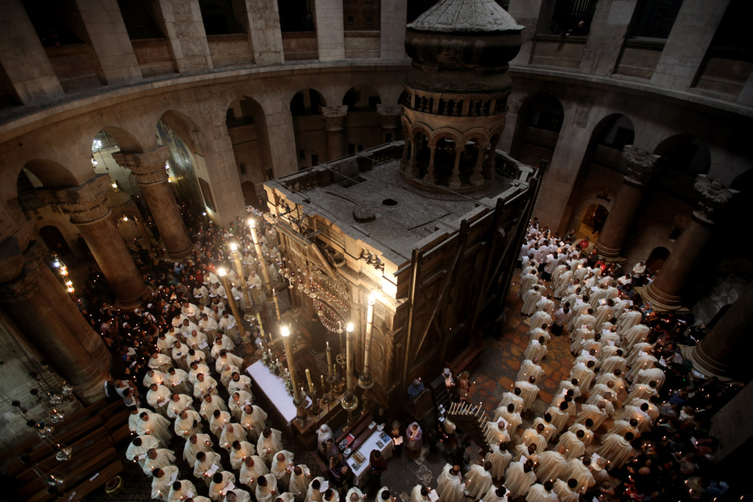 Roman Catholic clergymen hold candles as they circle the Aedicula during the Holy Thursday (Maundy Thursday) mass at the Church of the Holy Sepulchre in Jerusalem's Old City on March 24, 2016. / AFP PHOTO / GALI TIBBON
