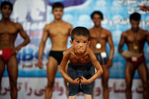 Enfant exposant ses muscles lors d'une compétition pour adultes