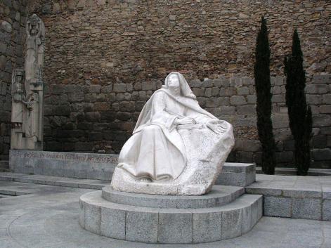Statue de marbre blanc, posée dans une cour, représentant une religieuse assise.