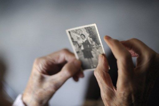 Une femme souffrant d'Alzheimer, regarde une photographie ancienne, dans une maison de retraire à Angervilliers. 