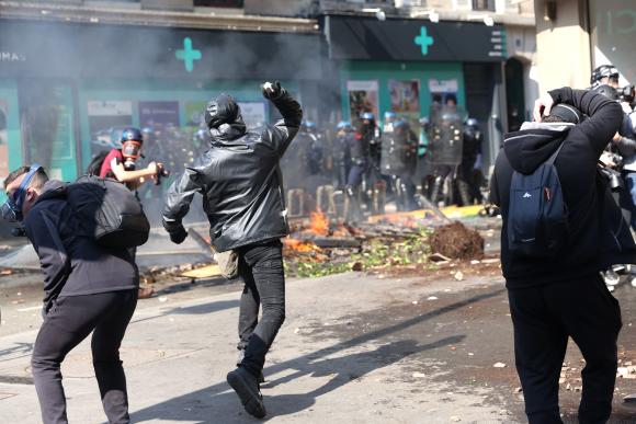 Un manifestant affronte des policiers et lance un projectile lors de la manifestation annuelle du 1er-Mai à Paris.