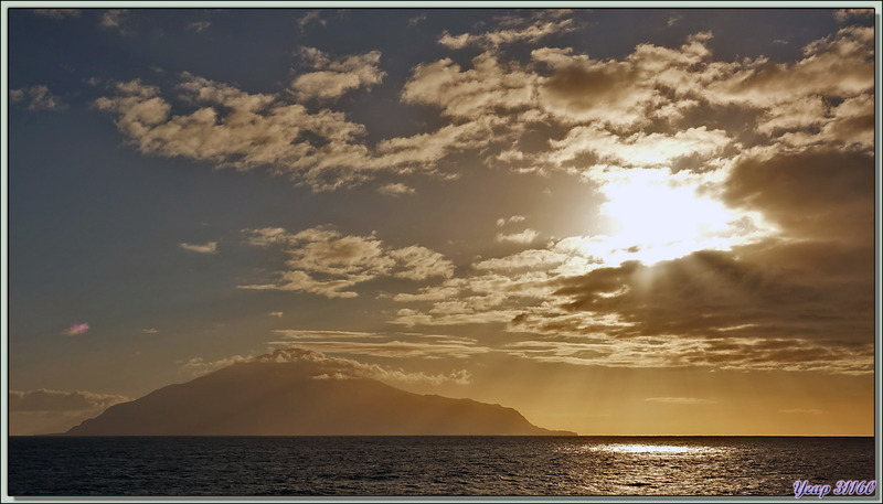 Le Lyrial navigue vers l'île Tristan da Cunha. Le sommet, The Queen Mary's Peak avec les lèvres du cratère du volcan, émerge des nuages 