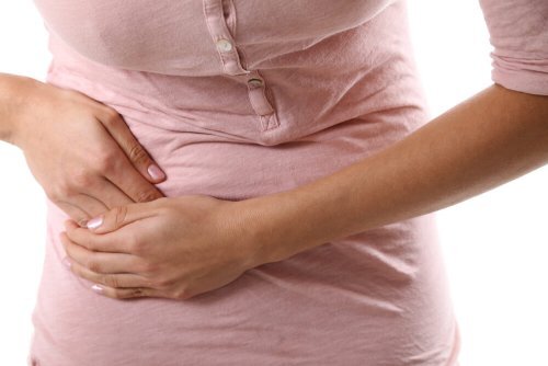 Femme avec la main droite posée sur la partie droite de l'abdomen