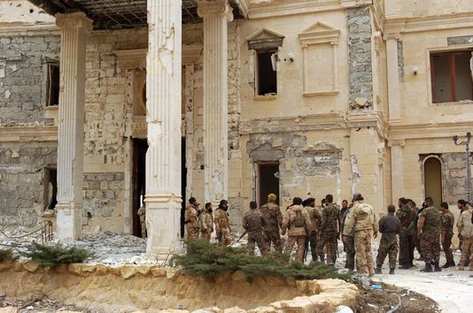 Des troupes de l'armée syrienne avancent vers un bâtiment appartenant à la famille royale qatarie, dans la périphérie de Palmyre, le 24 mars 2016.