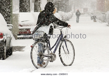 berlin-a-woman-pushes-her-bicycle-on-a-snowy-road-cw5h11