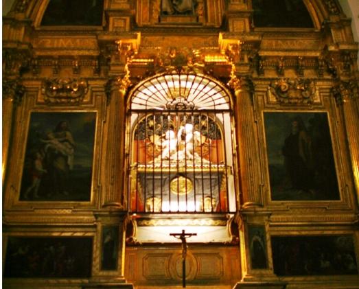 Tombeau ouvragé et éclairé situé dans une église.