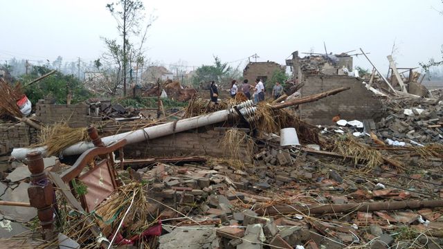 Des habitants de Yancheng, dans la province de Jiangsu à l'est de la Chine marchent dans les ruines des maisons détruites par des pluies torrentielles, de la grêle et des tornades, le 23 juin 2016