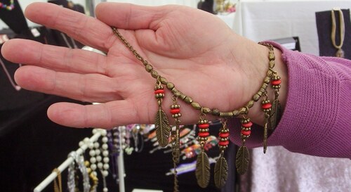 Le collier plumes de couleur bronze avec ses perles en bois rouges 