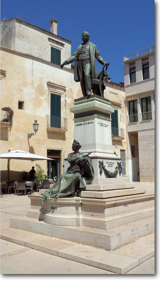 une statue, des balcons, une horloge, un lampadaire à Lecce 9/8