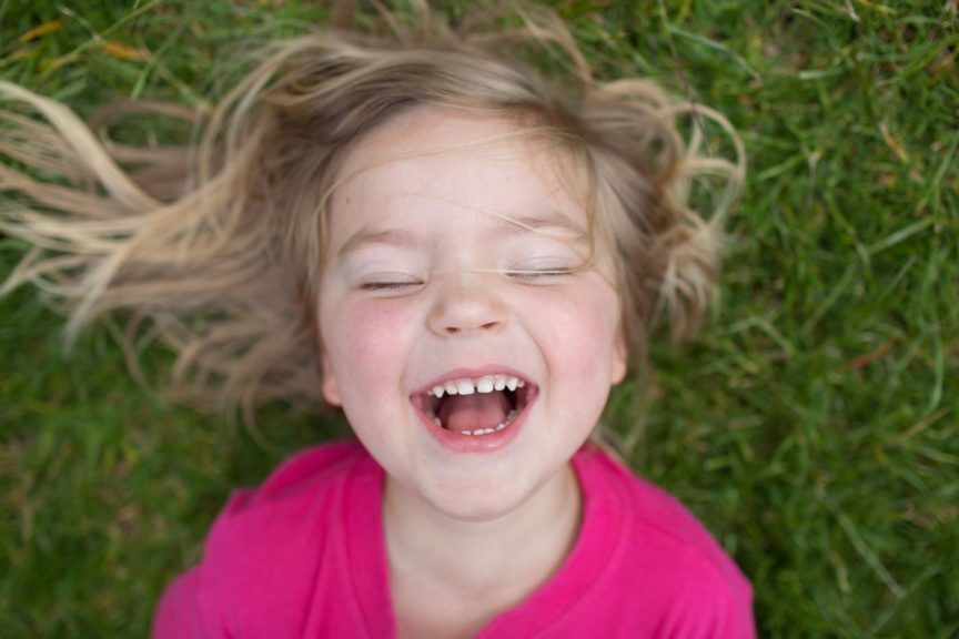 Enfant riant en étant allongé dans l'herbe