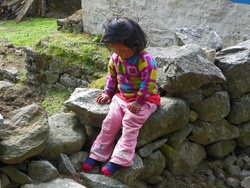 Petite fille assise sur un mur de pierres