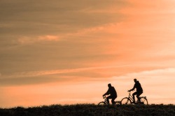 Les silhouettes de deux personnes faisant du vélo