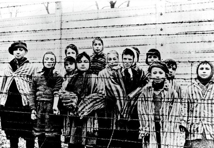 Un groupe d'enfants portant des uniformes de camp de concentration derrière des barbelés dans le camp de concentration nazi d'Oswiecim (Auschwitz)