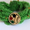 Bracelet vert avec des perles dorées et un bouton à fleur au milieu 10€