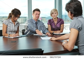 stock-photo-panel-of-business-people-sitting-at-table-in-meeting-room-conducting-job-interview-appli