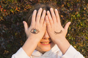 Fille avec des tatouages ​​pour les yeux sur la paume de la main qui couvre ses yeux Photo gratuit