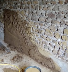 Création modélée en terre-paille sur mur en pierres