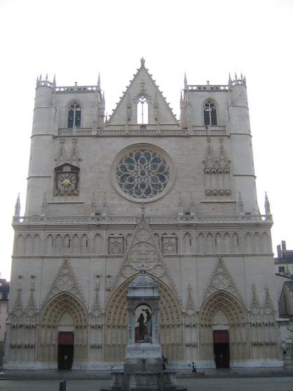 Photographie couleur de la façade d’une cathédrale, prise de face et de jour. Au premier plan, la fontaine du parvis.