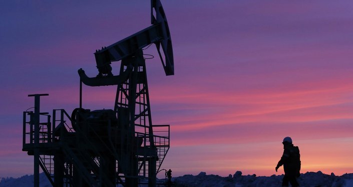 A worker walks past a pump jack on an oil field owned by Bashneft company near the village of Nikolo-Berezovka, northwest from Ufa, Bashkortostan, January 28, 2015