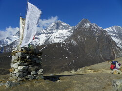 Un chorten surmonté d'un drapeau à prière devant des sommets himalayiens
