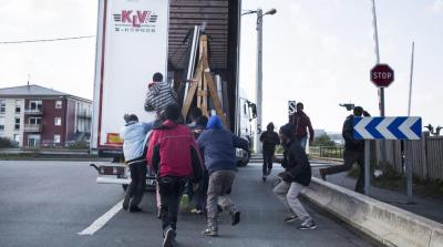 Des migrants profitent du fait qu'un camion à destination de l'Angleterre s'arrête à un stop pour tenter de s'introduire à l'intérieur, le 9 octobre 2014, à Calais.