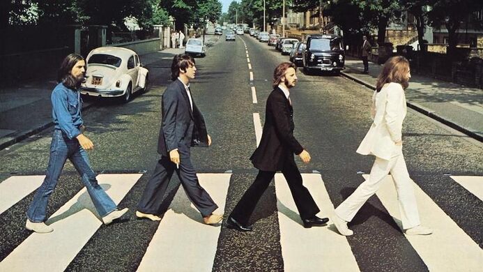 Les quatre membres de Beatles marchent l'un derrière l'autre sur un passage piéton.