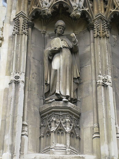 Photo de la statue d'un évêque mitré portant une image du Christ.