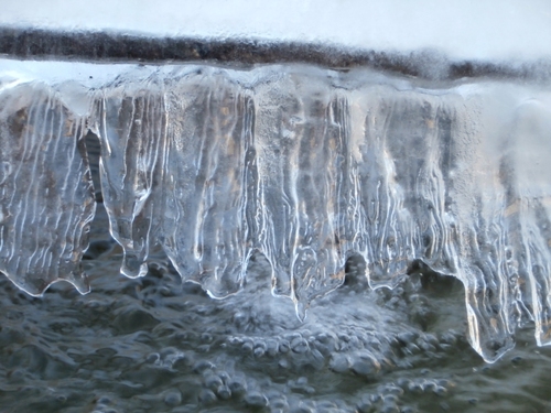 une draperie de glace translucide accrochée au-dessus de l'eau 