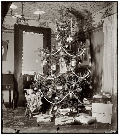 un arbre de noel des années 1900 avec des jouets devant le sapin