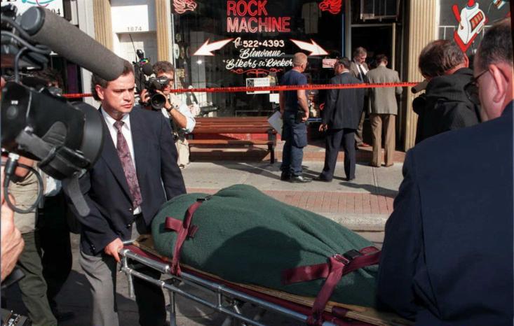 Des hommes transportent le corps d'un motard devant un commerce d'accessoires des Rock Machine.