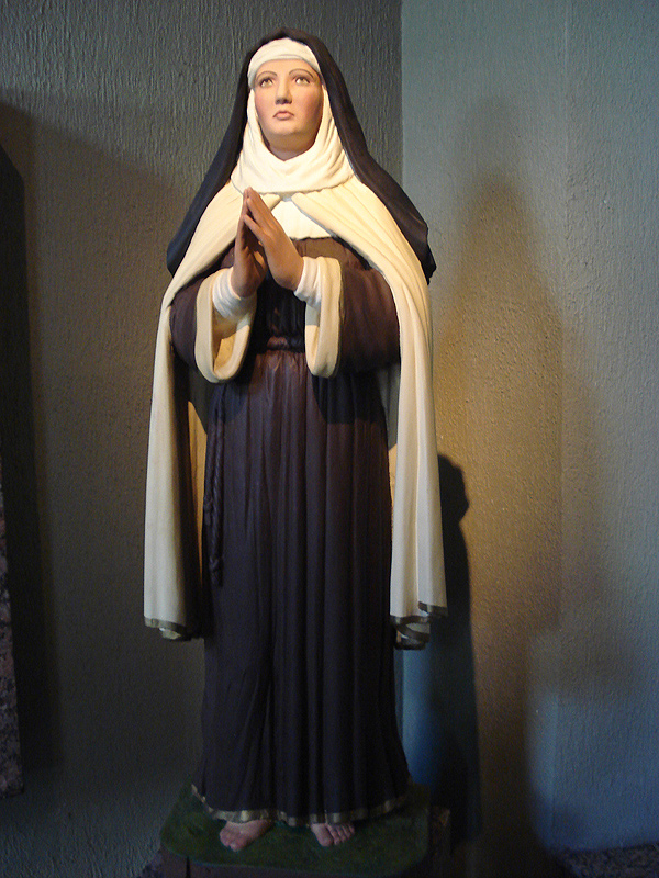 Statue polychrome d'une religieuse debout et en prière.